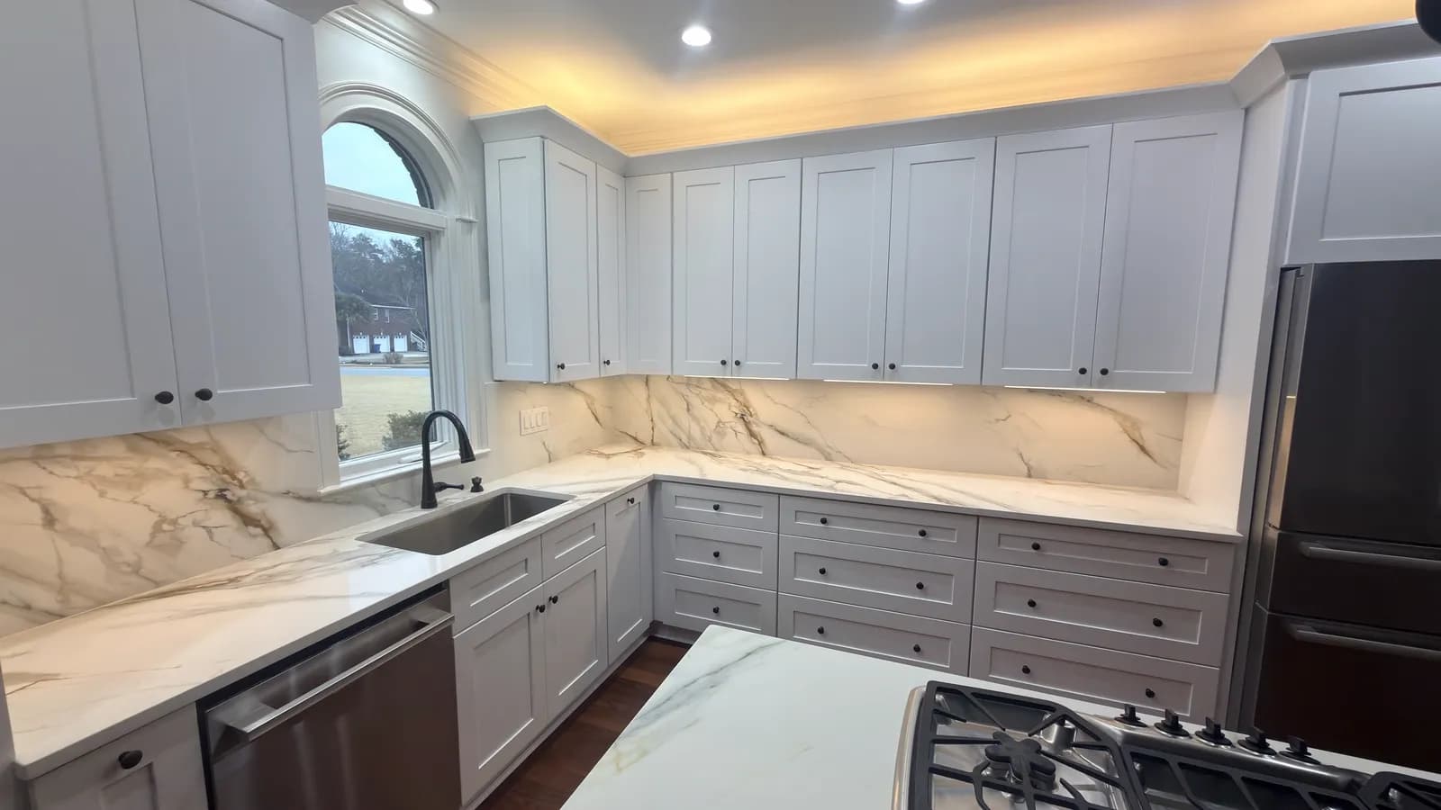 Grey and white kitchen with a book-matched marble backsplash and gas cooktop