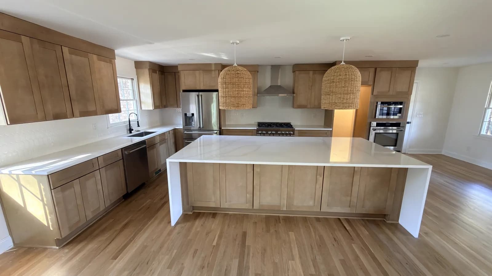 Natural stained oak kitchen with a large waterfall quartz island and rattan pendants