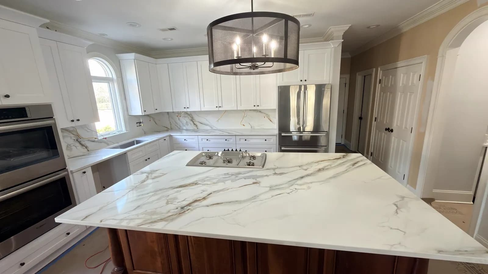White painted kitchen with a Calacatta quartz island and a dark stained island base