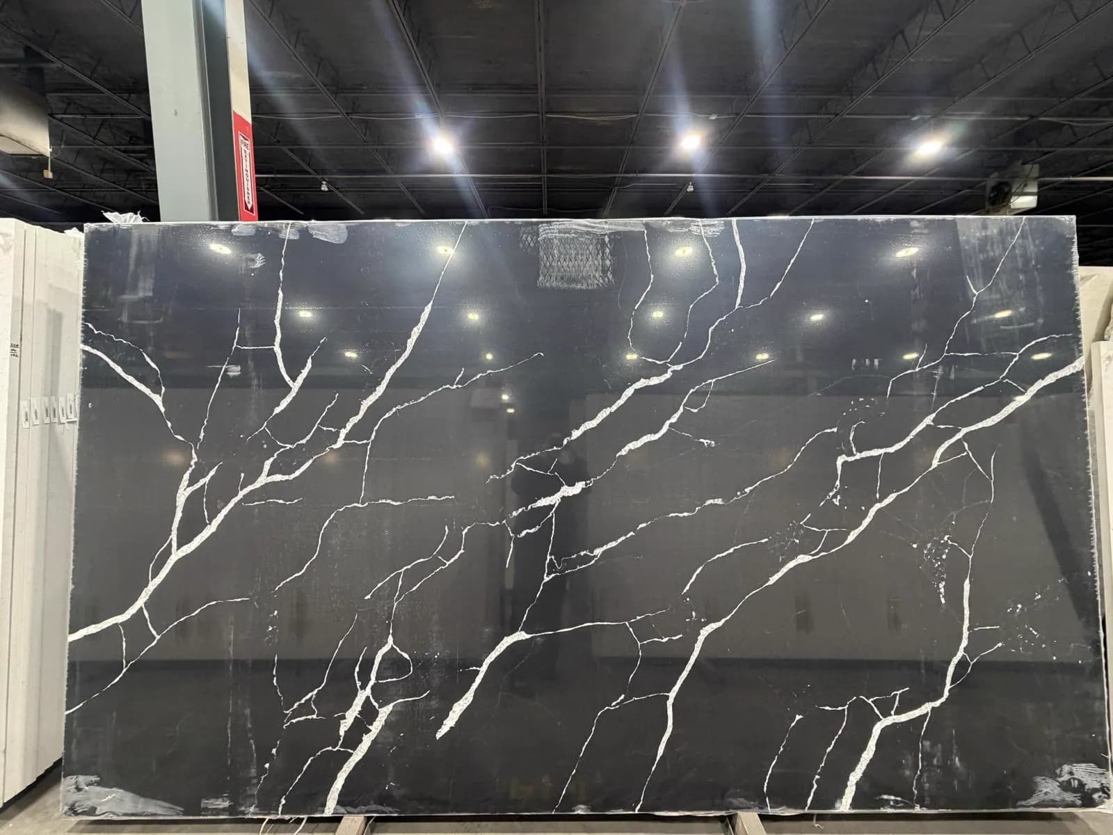 Black quartz slab with bold white veining, standing in the stone yard