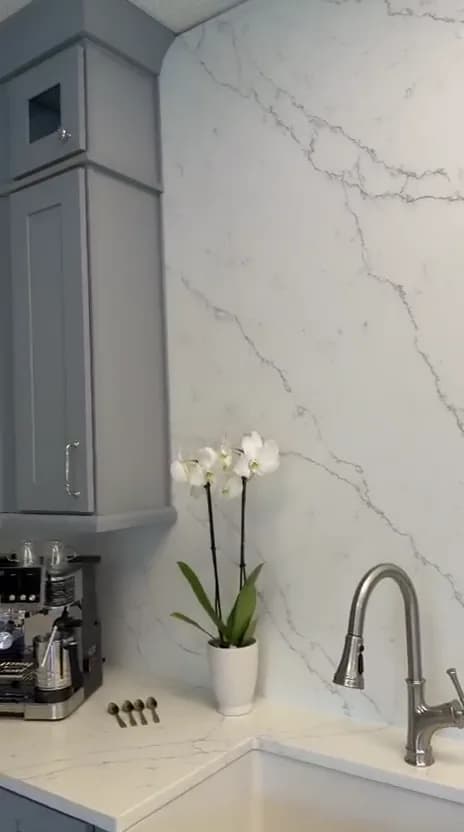 White quartz slab backsplash above a farmhouse sink in the showroom